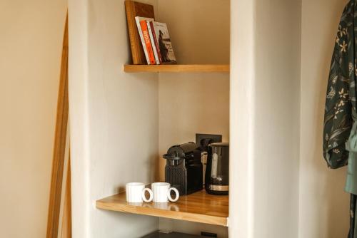 a shelf with coffee mugs and a coffee maker on it at Viento Luxury Apartments in Plomarion