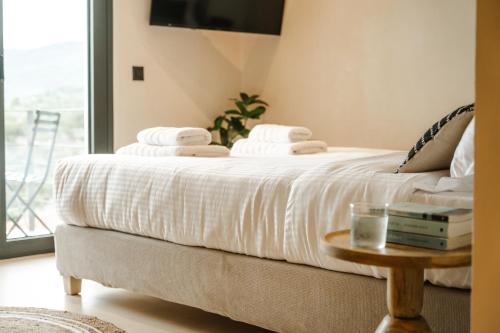 a bed with white sheets and a glass of water on a table at Viento Luxury Apartments in Plomarion
