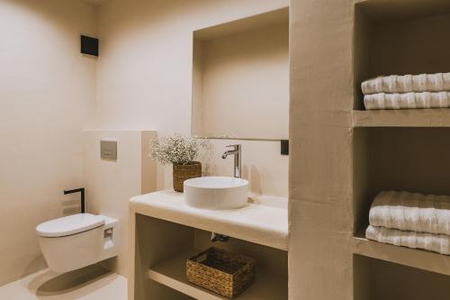 a bathroom with a sink and a toilet and towels at Viento Luxury Apartments in Plomarion