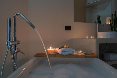a bathroom with a bath tub with a shower and candles at Viento Luxury Apartments in Plomarion