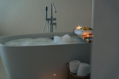 a bathroom with a bath tub with a sink at Viento Luxury Apartments in Plomarion