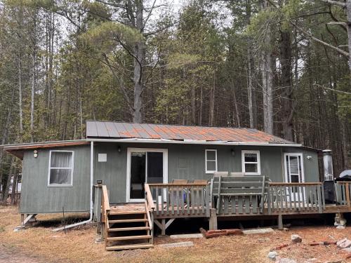 a green tiny house with a porch and a deck at The Shady Pine at New Frontiers Retreat in Eganville