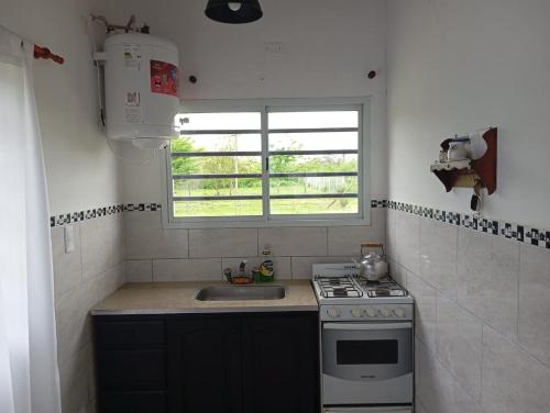 una cucina con un lavandino, un fornello e una finestra di El Quincho de Ampi a Chascomús