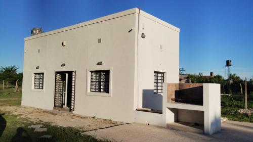 un edificio bianco con una porta e una finestra di El Quincho de Ampi a Chascomús