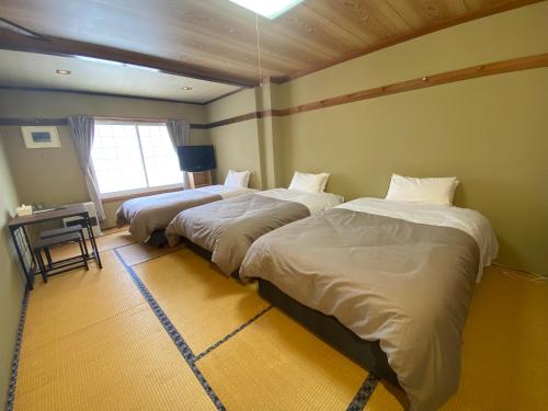 a bedroom with two beds and a table and a window at hareruya tsugaike in Chikuni