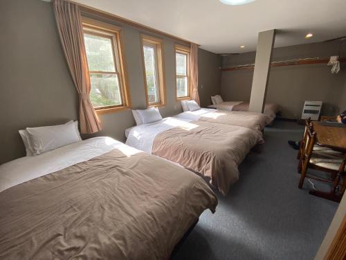 three beds in a room with windows at hareruya tsugaike in Chikuni