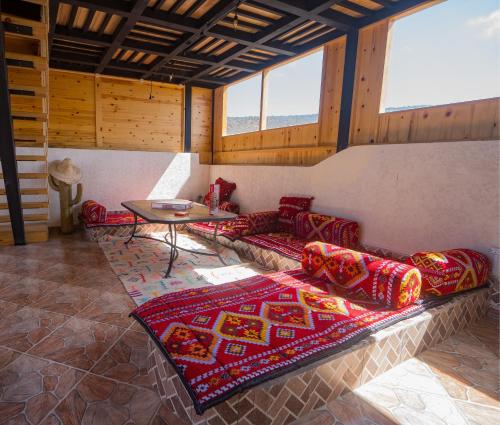 a living room with couches and a table and windows at Fu SPACE in Tamraght Ouzdar
