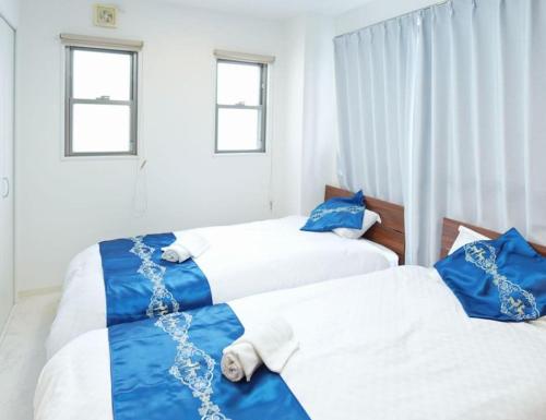 2 Betten in einem Schlafzimmer mit blau und weiß in der Unterkunft F House Os Residence S2 in Osaka