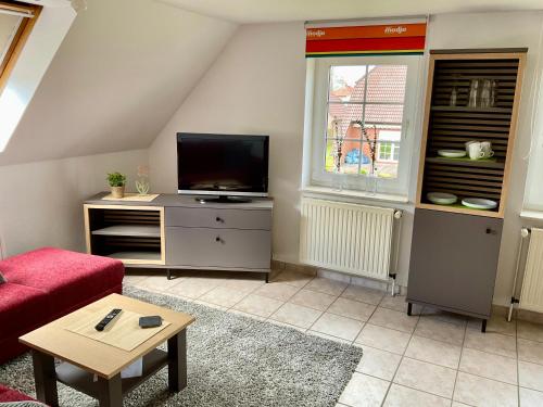 a living room with a tv and a red couch at Mein Nordlicht in Südbrookmerland