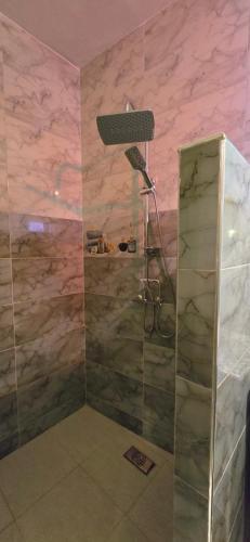 eine Dusche in einem Raum mit rosa Marmorwänden in der Unterkunft Riad Raffaa in Marrakesch
