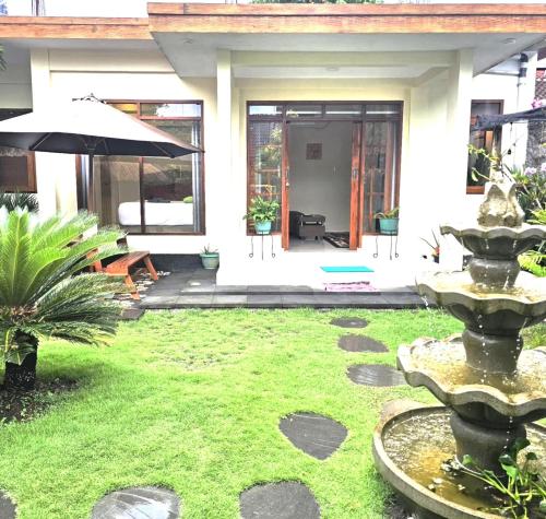 a garden with a fountain in front of a house at Suci's Friendly Apartments in Mataram