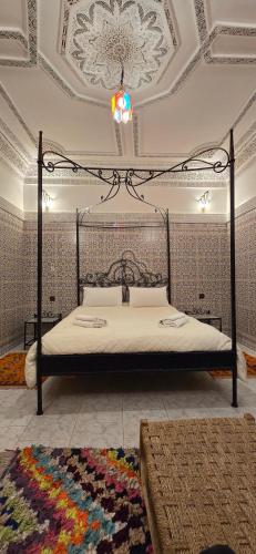 una camera da letto con un letto a baldacchino con un tappeto di Riad Raffaa a Marrakech