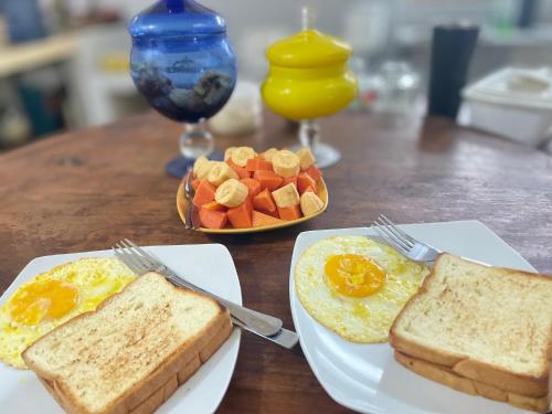 a table with two plates of eggs and toast and fruit at Lanina homestay in Ipi