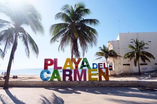 a sign on the beach with palm trees at Frida Downtown Apart in Playa del Carmen