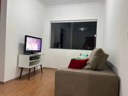a living room with a couch and a television at Confortável Apartamento em Condomínio in Pouso Alegre