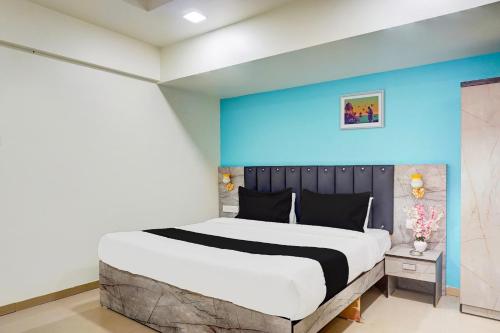 a bedroom with a large bed with a blue wall at Collection O Vardhan Plaza in Pune