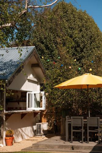 a yellow umbrella and chairs next to a house at The Casita at La Casa Cubo in Torquay