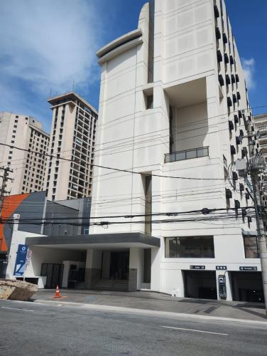 a white building on a street with tall buildings at Hotel Aeroporto Congonhas in Sao Paulo
