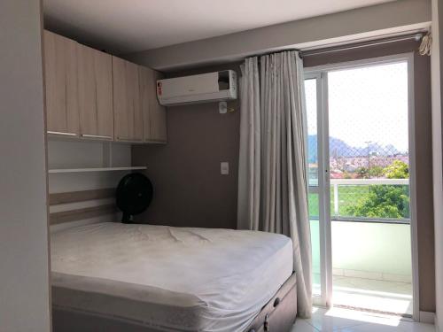 a small bedroom with a bed and a large window at Apto com Ar Cond e Wifi Super Confortável in Guarapari