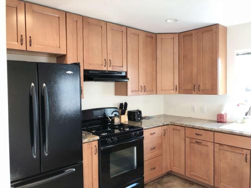 a kitchen with a black refrigerator and wooden cabinets at Nice house 10 minutes away to Disneyland or Knotts in Fullerton