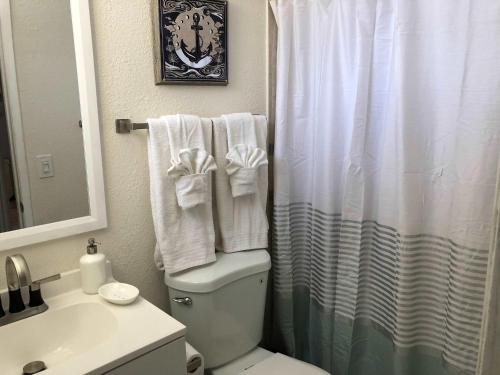 a bathroom with a toilet and a shower with towels at Nice house 10 minutes away to Disneyland or Knotts in Fullerton