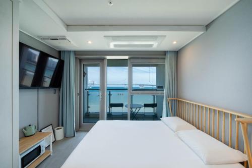 a bedroom with a large bed and a balcony at The First Hyoistay Gwangan in Busan