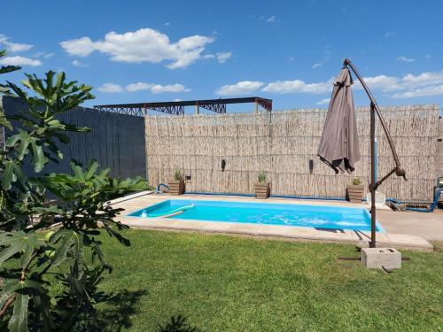 a swimming pool with an umbrella next to a wall at M&P alquiler por día in La Rioja