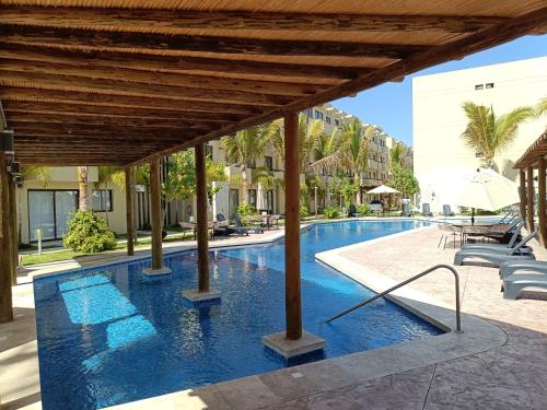 a pool at a resort with chairs and an umbrella at Enamórate in Mazatlán