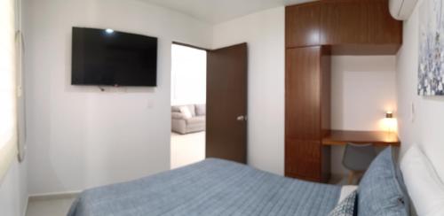 a bedroom with a bed and a flat screen tv at Enamórate in Mazatlán