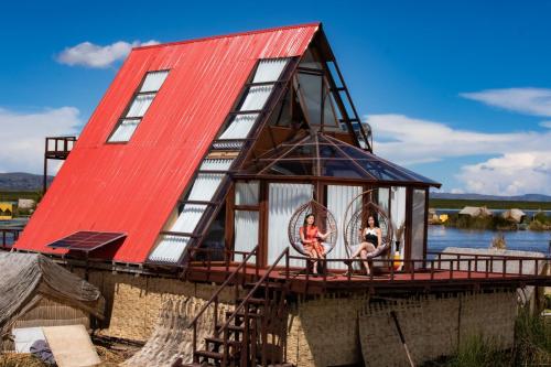 普诺Titicaca EcoLux的一栋红顶房子，两个人坐在露台上。