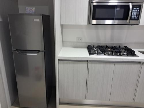 eine Küche mit einem Kühlschrank aus Edelstahl und einer Mikrowelle in der Unterkunft En el Centro de Matagalpa in Matagalpa