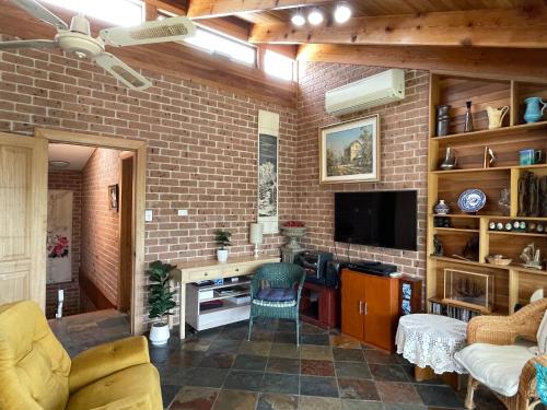 a living room with a tv and a brick wall at BasinWaterStays Waterfront Jetty - Brm3 in Basin View