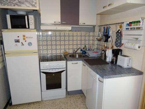 Il comprend une petite cuisine équipée d'une cuisinière et d'un évier. dans l'établissement Studio 25m² Climatisé au Cœur de Canet-en-Roussillon - FR-1-833-5, à Canet