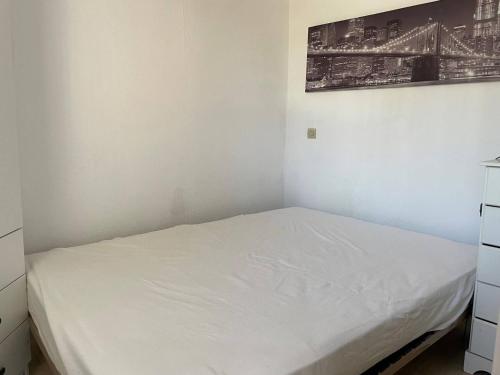 - une chambre avec un lit blanc et une photo sur le mur dans l'établissement Studio Cabine 4 Pers à 20m de la Plage - FR-1-833-3, à Canet