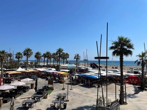 - une plage avec des tables, des parasols et des palmiers dans l'établissement Studio Cabine 4 Pers à 20m de la Plage - FR-1-833-3, à Canet