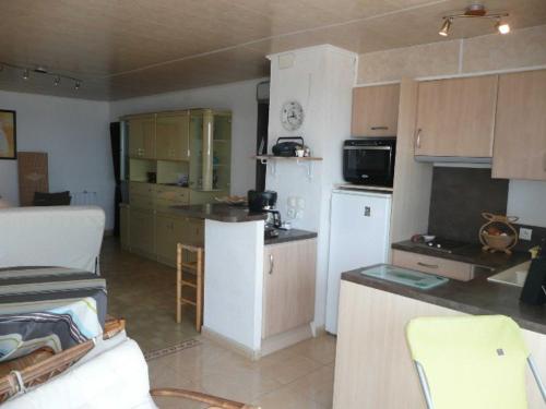 Elle comprend une petite cuisine équipée d'un réfrigérateur blanc et de placards. dans l'établissement Appartement 2P Climatisé Face Mer à Canet-en-Roussillon - FR-1-833-7, à Canet