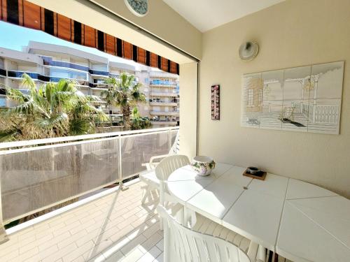 d'un balcon avec une table et des chaises blanches ainsi qu'une fenêtre. dans l'établissement Coquet T2 rénové en front de mer, animaux admis - FR-1-794-160, à Canet
