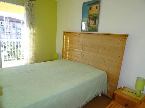 une chambre avec un lit avec une tête de lit en bois et une fenêtre dans l'établissement Appartement vue sur port avec parking et animaux admis - FR-1-833-6, à Canet