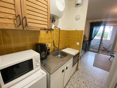 une petite cuisine avec un évier et un micro-ondes dans l'établissement Studio avec Parking Privé au Port de Canet - FR-1-833-12, à Canet
