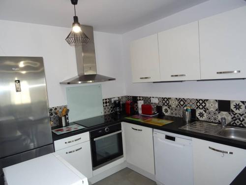 une cuisine avec des armoires blanches et des comptoirs noirs dans l'établissement T4 Proche Plage avec Garage, Climatisation - FR-1-833-14, à Canet