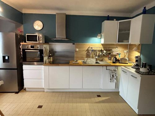 une cuisine avec des armoires blanches et un mur bleu dans l'établissement Grand T2 moderne avec balcon - Proche plage, clim et parking - FR-1-833-30, à Canet