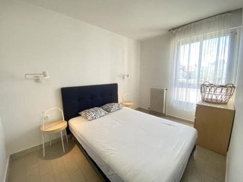 - une chambre avec un lit doté d'une tête de lit bleue et d'une fenêtre dans l'établissement Appartement 2 pièces climatisé avec WIFI près de la plage - FR-1-833-16, à Canet