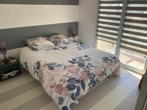 - un lit avec une couette à fleurs dans une chambre dans l'établissement Magnifique T3 Climatisé avec Parking Canet-en-Roussillon - FR-1-833-10, à Canet