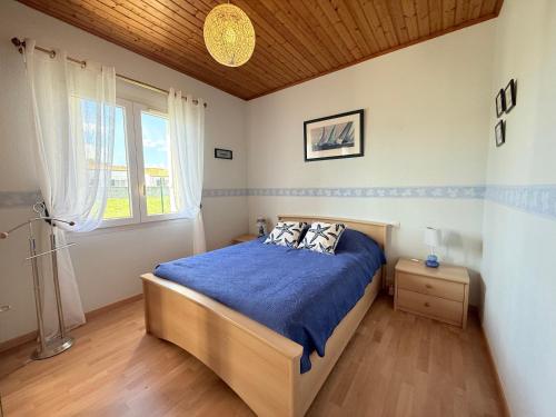 a bedroom with a bed with a blue comforter and a window at Maison familiale proche plages et commerces avec jardin - FR-1-778-48 in Dolus-d'Oléron