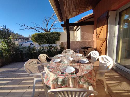 une table et des chaises assises sur une terrasse avec une table et des chaises dans l'établissement Villa T3 Mezzanine - Parking Privé - À 6 min de la plage - 6 pers. - Narbonne-Plage - FR-1-795-62, à Narbonne