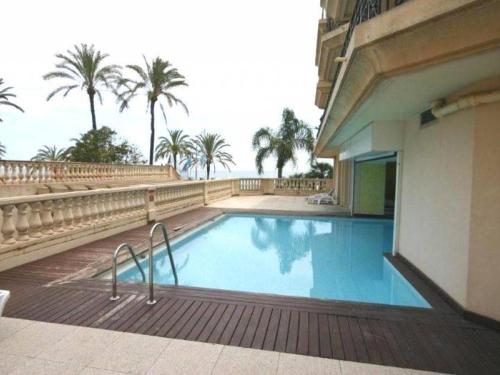 - une piscine à côté d'un bâtiment avec des palmiers dans l'établissement Spacieux 3P en centre-ville avec terrasse vue mer à Menton - FR-1-196-379, à Menton