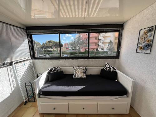 un lit dans une chambre avec une grande fenêtre dans l'établissement T2 Bord de Plage - 4 Pers - Parking Privé - FR-1-81-635, à Port-Leucate