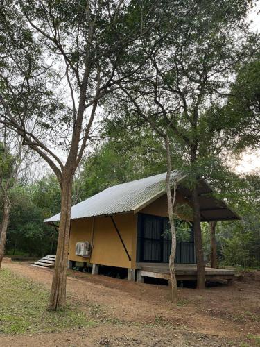 a building with a metal roof in the middle of trees at Kalandaka Villas Anuradhapura in Anuradhapura