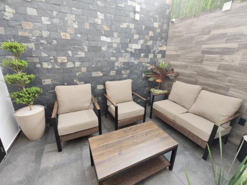 a patio with three chairs and a table and a brick wall at Hotel HS Confort in Orizaba