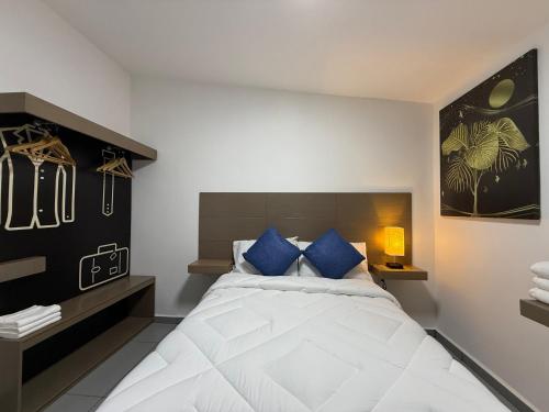 a bedroom with a large white bed with blue pillows at Hotel HS Confort in Orizaba